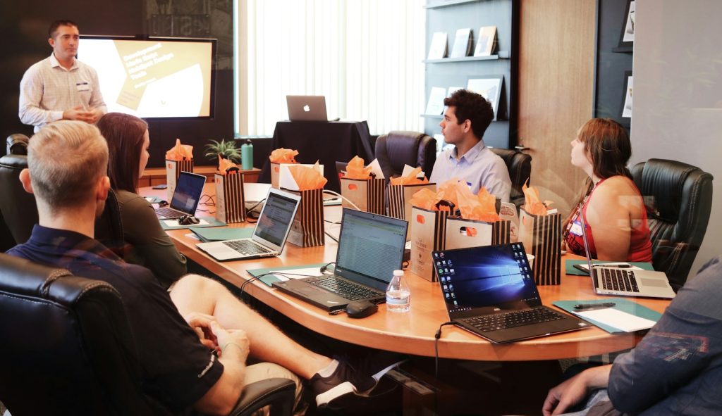 man standing in front of people sitting beside table with laptop computers