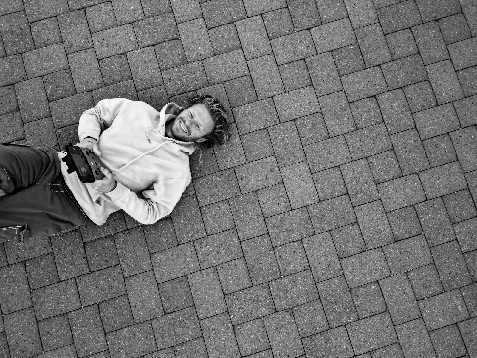 Man lying on brick ground holding a camera