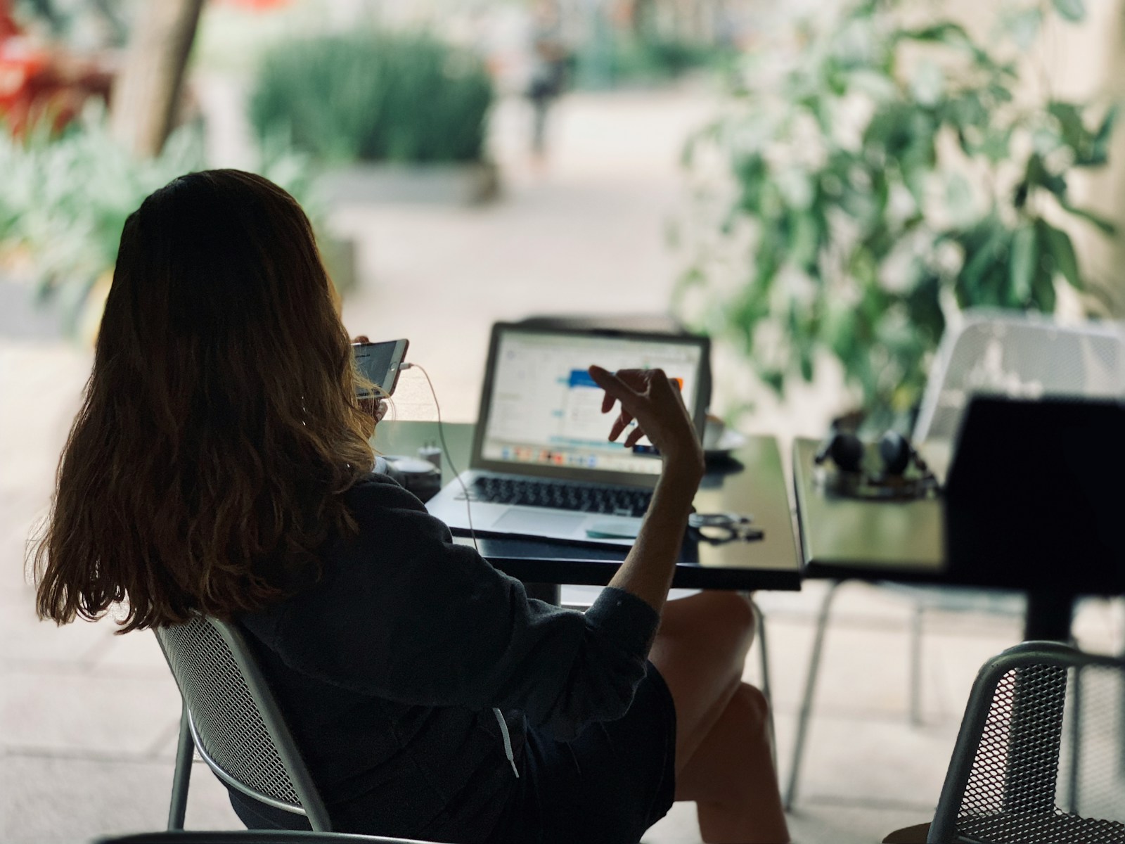Frau sitzt auf dem Stuhl vor dem Tisch mit Laptop