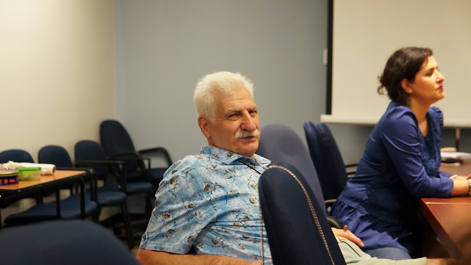 An older man and woman in a meeting room.