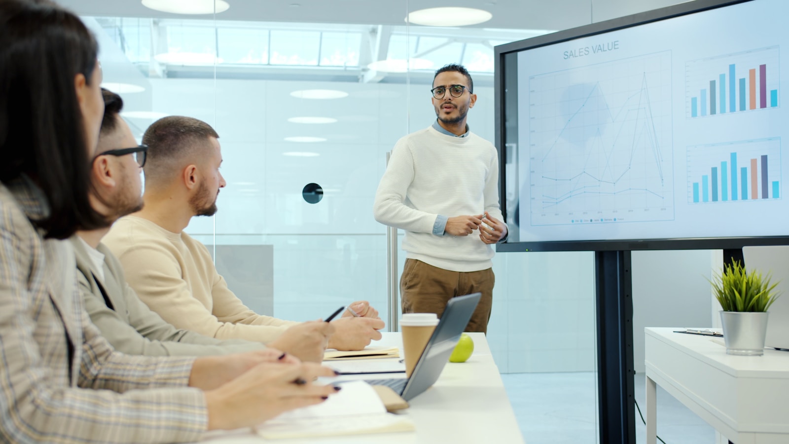 Man presenting charts to colleagues in a meeting.